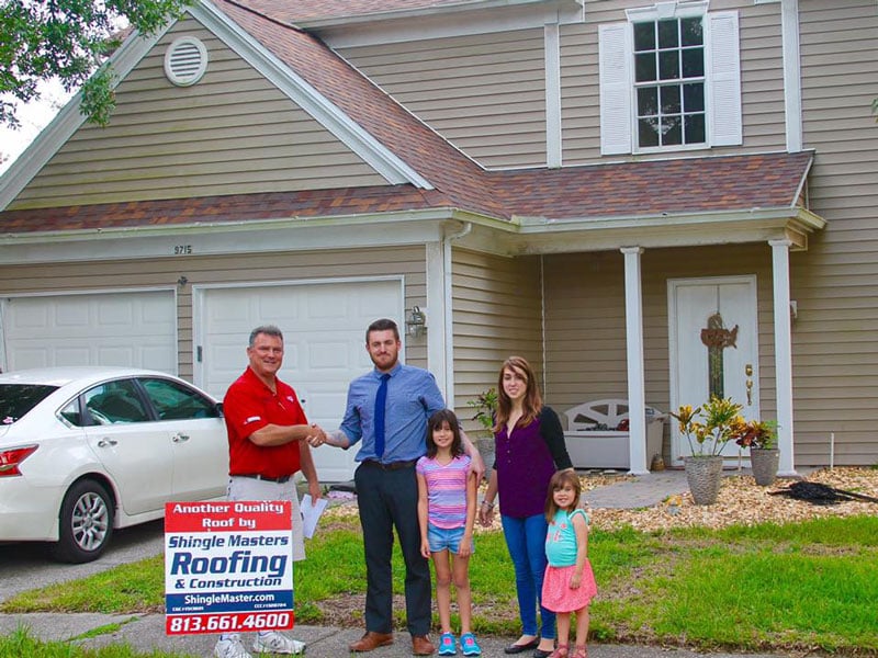 family shaking hands of worker outside home