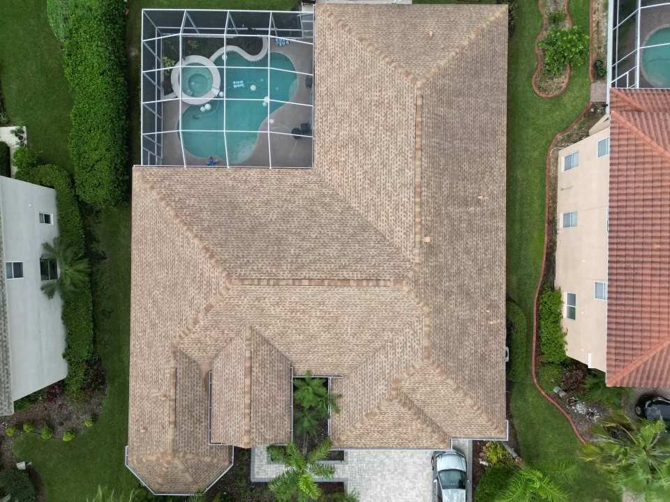 Top-down view of a brown shingled roof on a large home that was installed by Shingle Masters Roofing and Construction with adjacent lawns, pool in Tampa, FL
