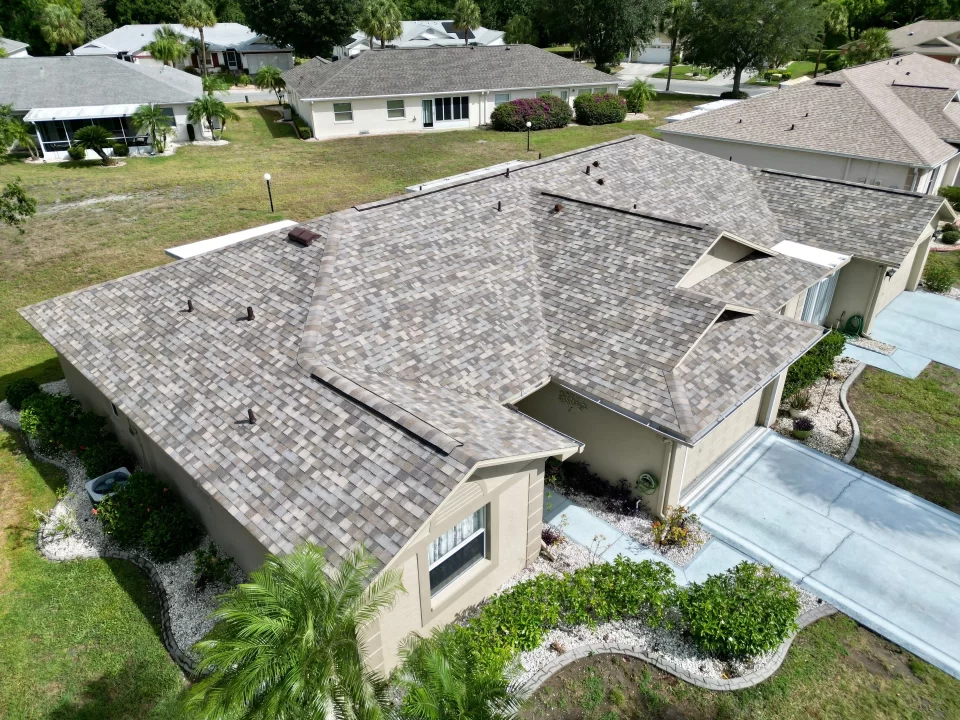 Aerial view of a beige home with a complex, multi-angled gray shingle roof installed by Shingle Masters Roofing & Construction in Riverview, Florida.